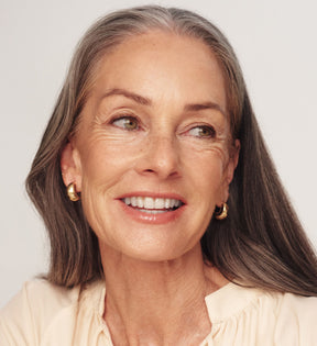 The Valentines Bundle featuring The Soft Tan Bronzer on a smiling model with gray hair for a radiant glow.