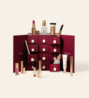 Advent Calendar - 12 Days of Effortless Beauty featuring a burgundy box with drawers and assorted makeup products displayed on cream.