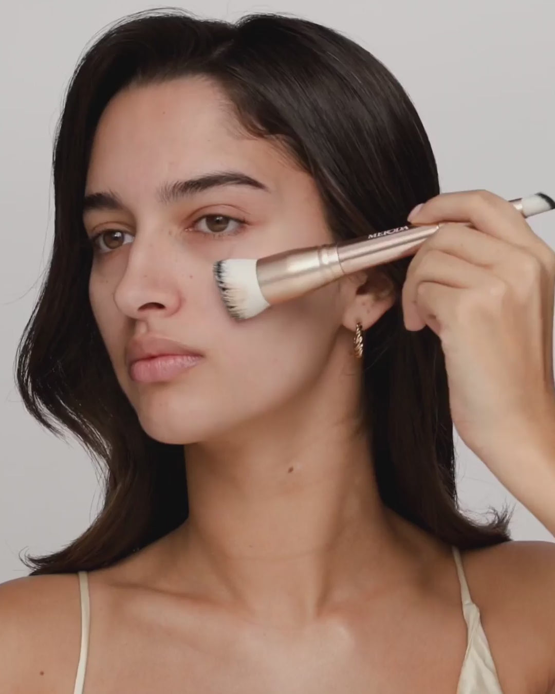 Model applying Changing Foundation with a dual-ended brush, followed by holding the foundation bottle.