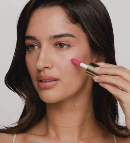 Vibrant Cheek Blush in pink being applied and blended with a brush for a fresh glow.