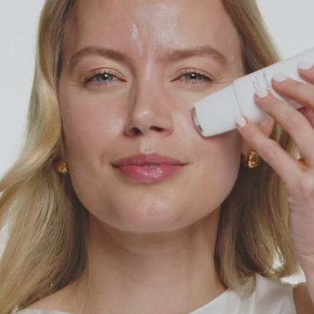 Model applying Daily Face SPF 40 with a cooling metal roller applicator onto her cheek.