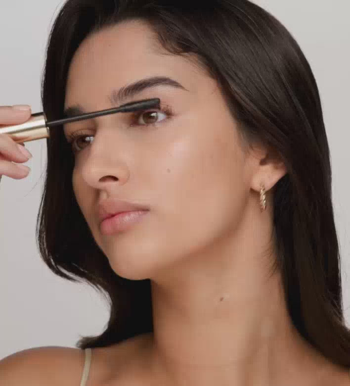 Model applying Gilded Lashes Mascara to define and lift lashes for an everyday look.