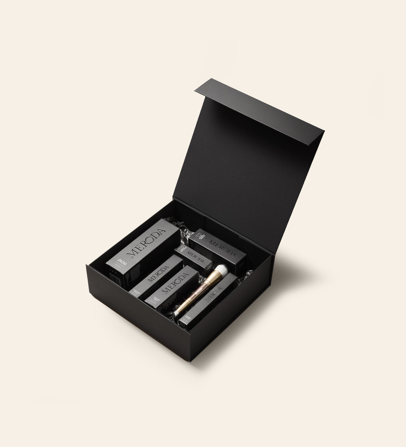 Matte black Gift Box with a magnetic closure filled with Meroda Cosmetics products and a gold makeup brush.