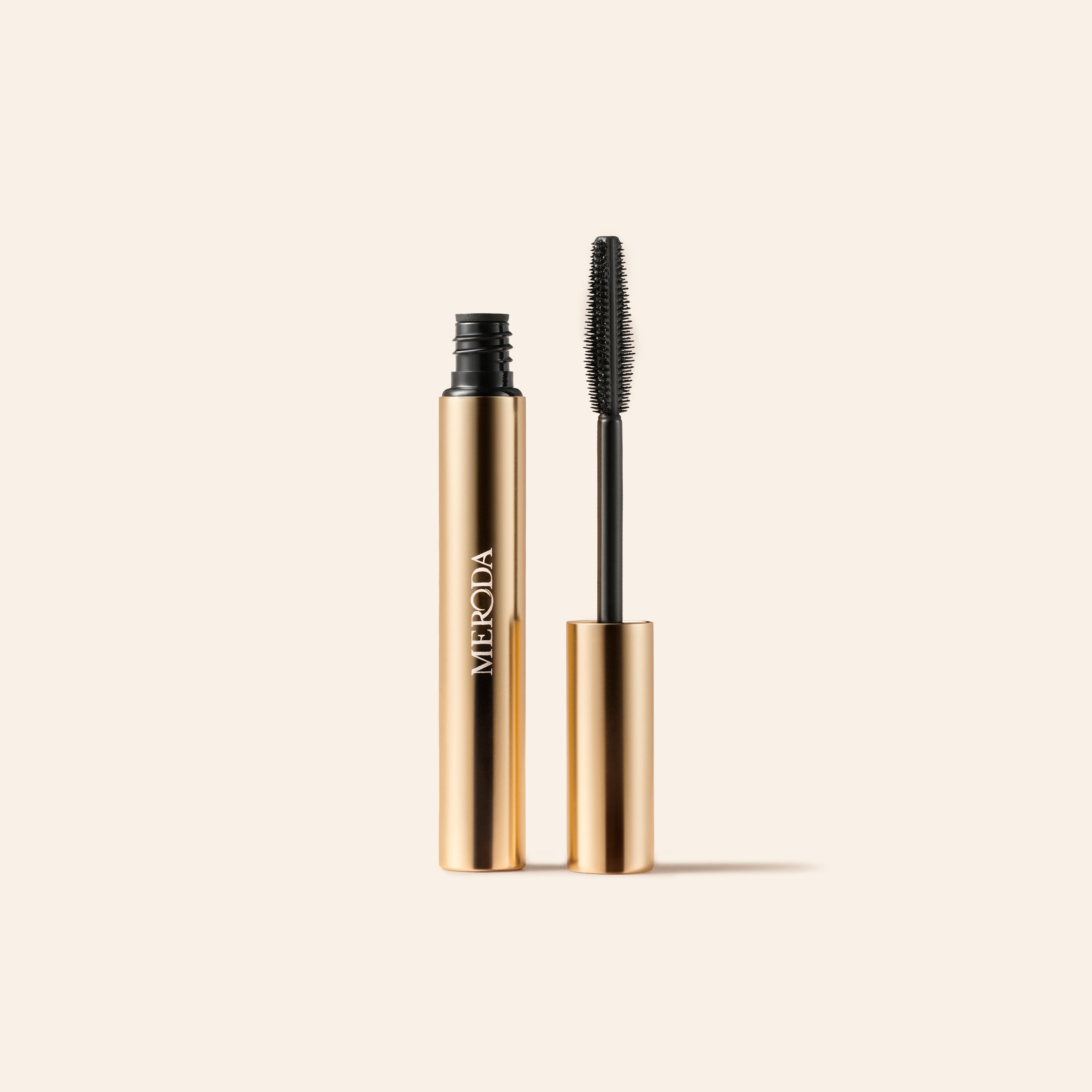 Meroda Cosmetics Mini Mascara in a gold tube with a black wand applicator for lengthening and volumizing lashes.