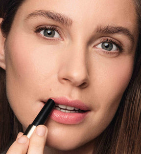 Woman applying Meroda Cosmetics Hydrating Lip Tint in Peachy Rose for a fresh, natural look.