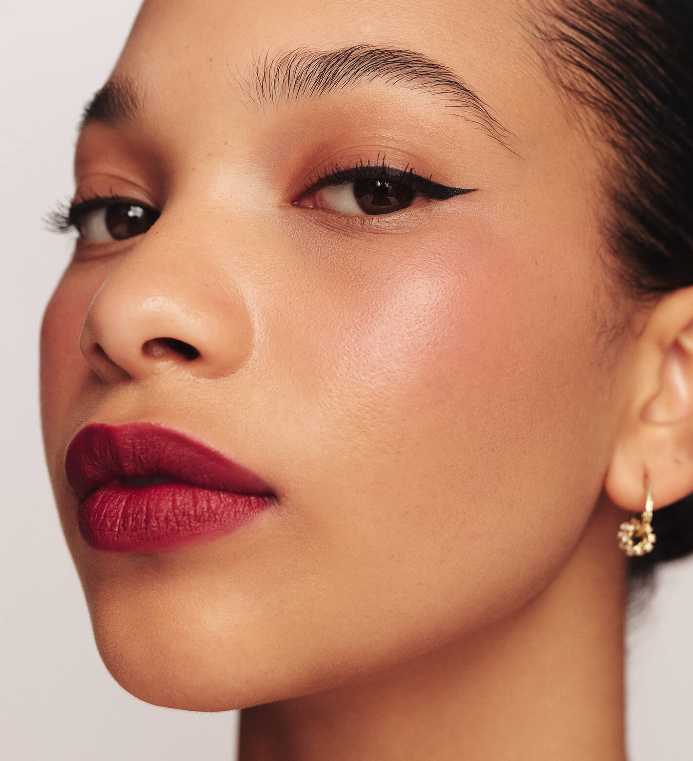 Meroda Cosmetics It's All About The Wing Liquid Waterproof Eyeliner on a model with a precise wing and matte berry lipstick