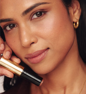 Meroda Cosmetics Soft Tan Bronzer in shade Dark held by a model for a natural, sun-kissed glow and radiant finish.