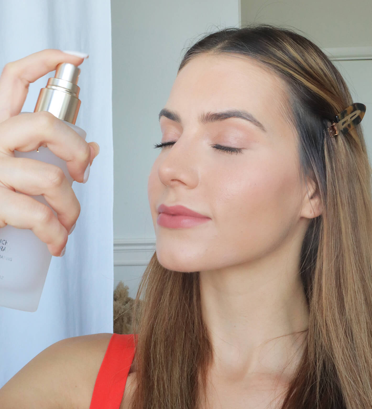 Woman applying Meroda Cosmetics Final Touch Setting Spray to hydrate skin and lock in a radiant makeup finish.