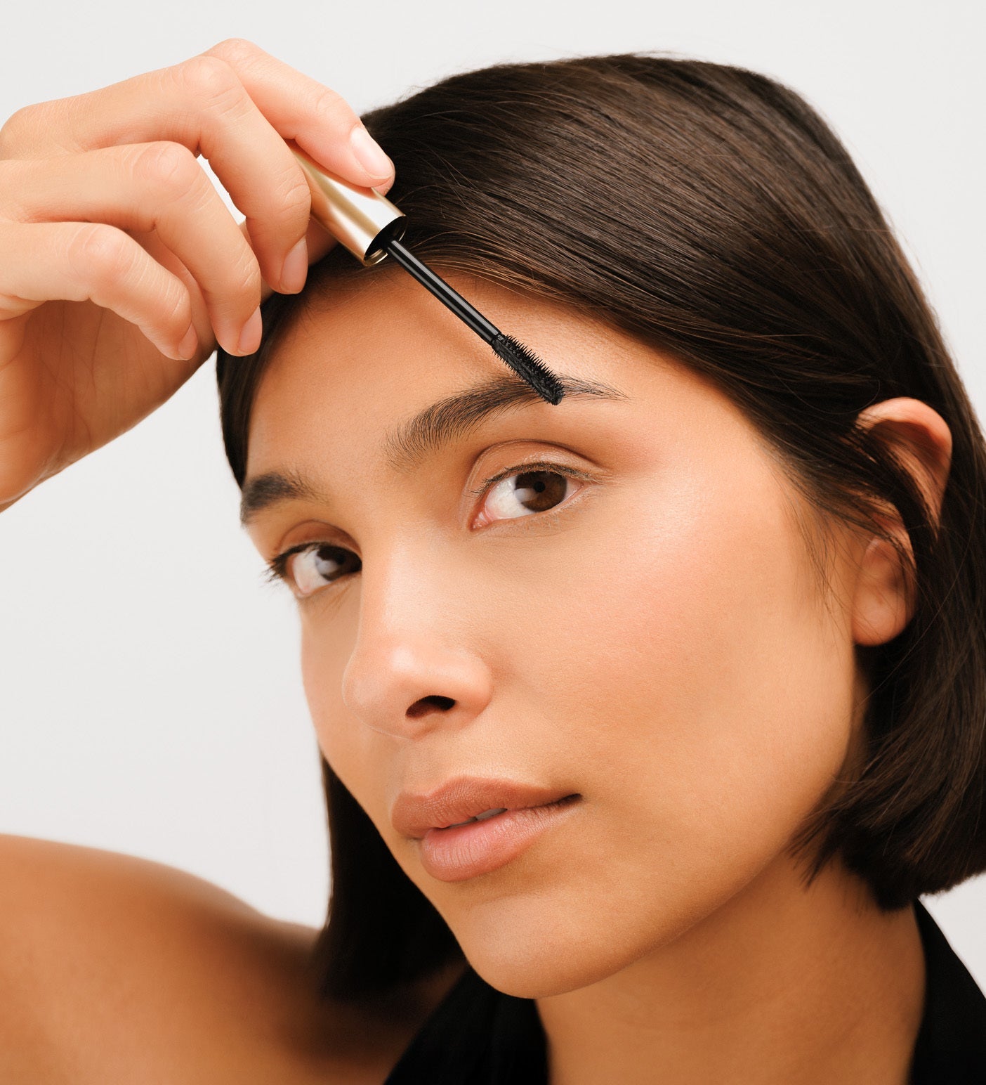 Model applying The Precision Brow Gel to lift and set eyebrows for a natural, polished look
